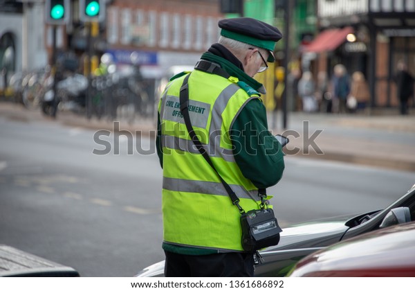 civil enforcement officer or traffic warden\
with glasses in typical English\
town