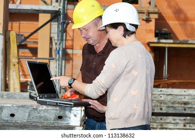 Civil engineer and construction worker looking at the laptop