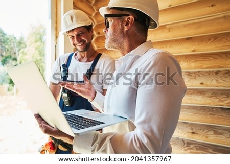 Civil engineer with laptop explaining something to housebuilder