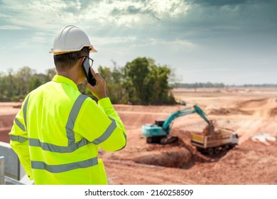 A civil engineer working on the construction site in the background with loaders and dumpers.