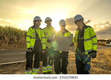 Civil engineering contractors coordinating wind farm site operations during golden hour. Professional project management team reviewing blueprint logistics for utility infrastructure.