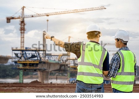 A Civil engineering team working near the construction site of a highway bridge over a river. Engineers inspecting the construction site of a high bridge over a river. Land transportation.