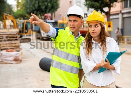 Civil engineers checking work process in construction site outdoors, comparing to blueprints