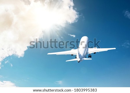 Civil plane took off into the blue sky and flies away into the bright rays shine the sun in the clouds.