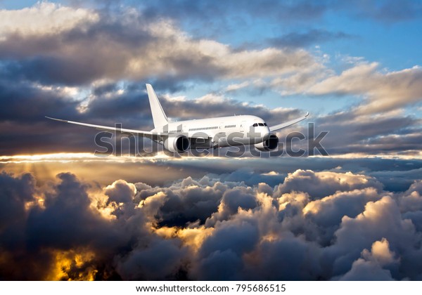 Civil wide-body airplane. Aircraft\
flying on a high altitude above the clouds during\
sunset.