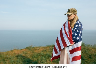 Civilian Woman In Her Husband's Military Cap. A Widow With A Flag Of The United States Left Without Her Husband. Memorial Day To Fallen Soldiers In The War. May 27th Is A Memorial Day.