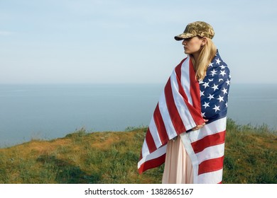 Civilian Woman In Her Husband's Military Cap. A Widow With A Flag Of The United States Left Without Her Husband. Memorial Day To Fallen Soldiers In The War. May 27th Is A Memorial Day.