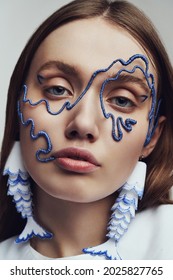 Ckose up portrait of woman in blue wire mask and with blue and white fish earrings. Creative accessories on marine theme                                                      - Shutterstock ID 2025827765