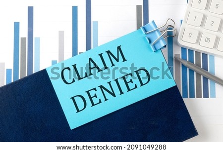 CLAIM DENIED on sticky note on the notebook on the chart background
