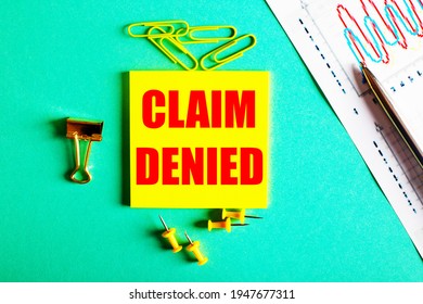 CLAIM DENIED is written in red on a yellow sticker on a green background near the graph and pencil - Shutterstock ID 1947677311