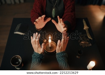 Clairvoyant and client holding hand over candle flame top view