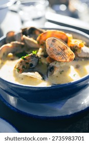 Clam chowder in a bowl with lots of in shell clams