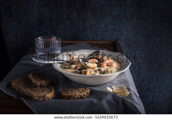 Clam chowder in a\
white plate. The main ingredients are shellfish, broth, butter,\
potatoes and onions.