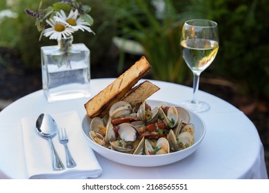 A clam and pasta dish with wine in outdoor setting - Powered by Shutterstock