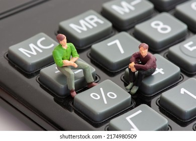 Clamart, France - July, 4, 2022: Two figurines sitting on calculator keys next to the percentage sign and talking about the concepts of interest rates, growth, recession, and inflation percentage