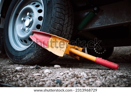 A clamp is used to secure a front wheel of the automobile during transportation, repair. Orange and red wheel blocker. A locker for a car, automobiles. Unpaid parking. Booted vehicle on a city street.