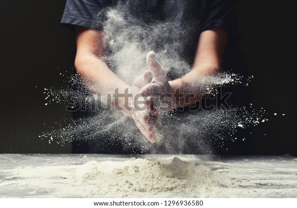 Clap\
hands of baker with flour in restaurant\
kitchen