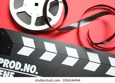 Clapboard And Reel With Foil On Red Background, Flat Lay. Video Production Equipment