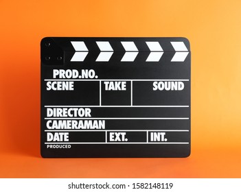 Clapper board on orange background. Cinema production - Shutterstock ID 1582148119