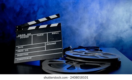 Clapper board and reels with film in clouds of smoke in blue neon light. Concept of film making. - Powered by Shutterstock