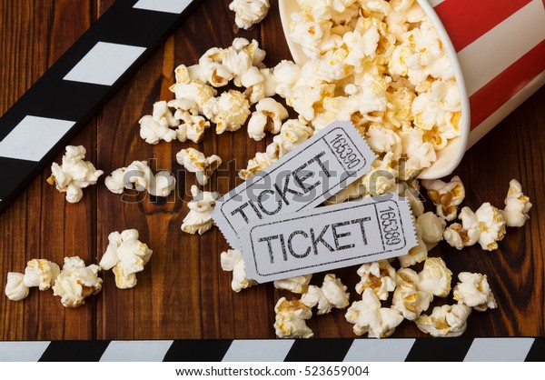 Clapper board, spilled popcorn and movie tickets\
on a background of\
boards