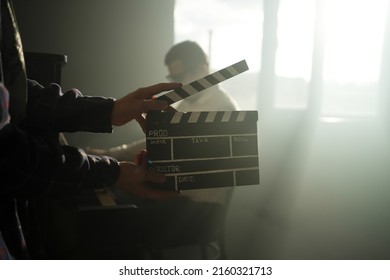 Clapperboard Or Clipboard In Hands. Guy Is Directing And Filming Retro Cinema Or Vintage Movie. Composer Man Play On The Old Piano.