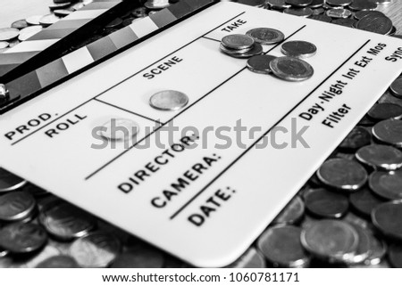 Clapperboard with coins above and on it creating a relation between filmmaking and business [Black and White version]