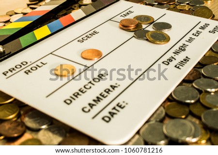 Clapperboard with coins above and on it creating a relation between filmmaking and business