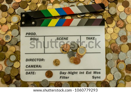 Clapperboard with many coins surrounding, above and on top of it