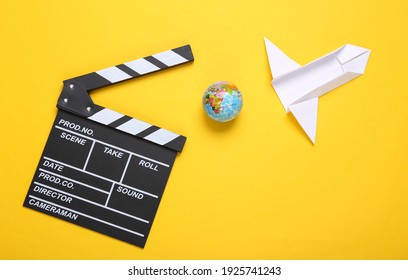 Clapperboard And Origami Rockets, Globe On A Yellow Background. Science Fiction Film. Top View