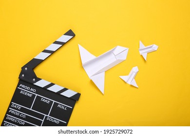 Clapperboard And Origami Rockets On A Yellow Background. Science Fiction Film. Top View