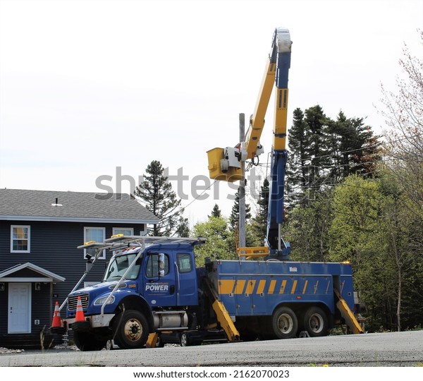 Clarenville\
Newfoundland and Labrador - May 30, 2022 - Hydro energy company\
Newfoundland Power cherry picker truck with crane extended and crew\
making repairs after a power\
outage.