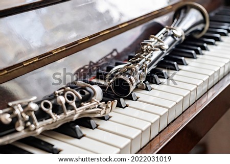 The clarinet, disassembled in half, lies on the piano by the sunny window.