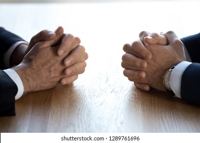 Clasped hands of two business men negotiators opponents opposite on table as politicians dialogue debate, applicant hr job interview, negotiating competitors, rivals confrontation challenge concept