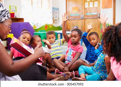 Class Of Preschool Children Raising Hands To Answer Teacher