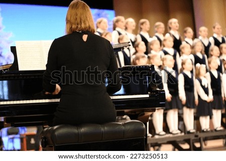 Classes of the choir of children standing on the stage with a teacher at the piano.Background image of kids creative development