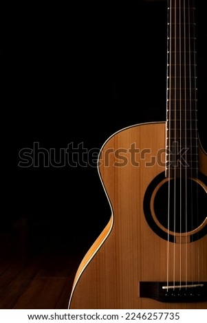 Classic Acoustic guitar close up, dramatically lit on a black background with copy space