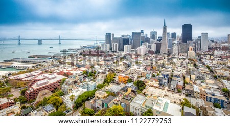 Classic aerial view of modern San Francisco skyline in summer with famous San Francisco fog rolling in seen from historic Coit Tower, San Francisco Bay Area, California, USA