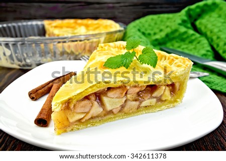 Classic American apple pie with whipped cream in a plate with cinnamon, napkin, glass form on a wooden boards background