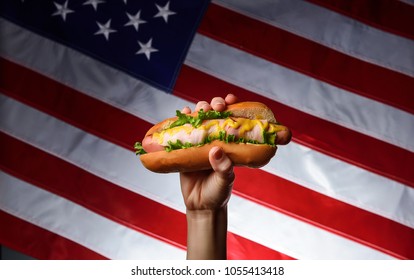 classic american hot dog in hand on american flag background - Powered by Shutterstock