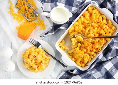 Classic Baked Homemade Macaroni And Cheese In Baking Dish And On Plate With Fork. Grated Cheddar Cheese  And Jug With Fresh Cream On Wooden Table, View From Above, Close-up