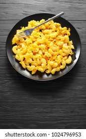 Classic Baked In Oven Homemade Mac And Cheese Served On Black Plate With Fork On Dark Wooden Table, Vertical View From Above