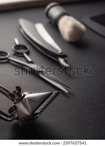 Classic barber tools including scissors, a straight razor, and a shaving brush are neatly organized on a dark surface, emphasizing traditional grooming techniques used by barbers.