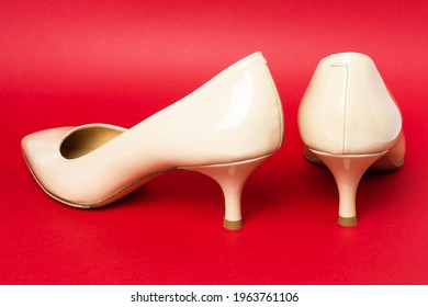 Classic Beige Patent Leather Shoes  With Kitten Heels On Red Background, Back View.