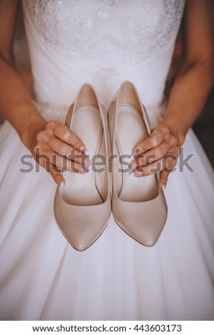 classic beige shoes, in the hands of the girl, background white dress