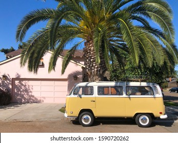 Classic beige and white vintage Volkswagen T1 camper van parked in front of pink house. San Diego, California, USA. July 13th, 2019