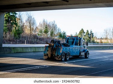 Classic Big Rig Blue Semi Truck Day Cab Tow Tractor With With Boom And Other Towing Equipment Moving On The Highway Road Intersection With One Way Traffic Direction At Sunny Day To The Accident Site 