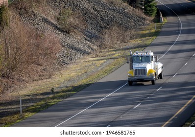 Classic Big Rig White Semi Truck Day Cab Tow Tractor With Boom And Other Towing Equipment Moving On The Highway Road Intersection With One Way Traffic Direction At Sunny Day To The Accident Site