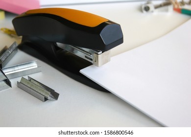 Classic black office stapler with documents. In the work field.