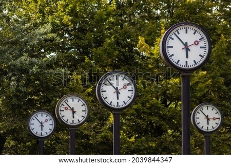 Classic black and white analog clocks with synchronized time show teamwork and synced project management with time management and deadlines in international teams running out of time ticking clocks